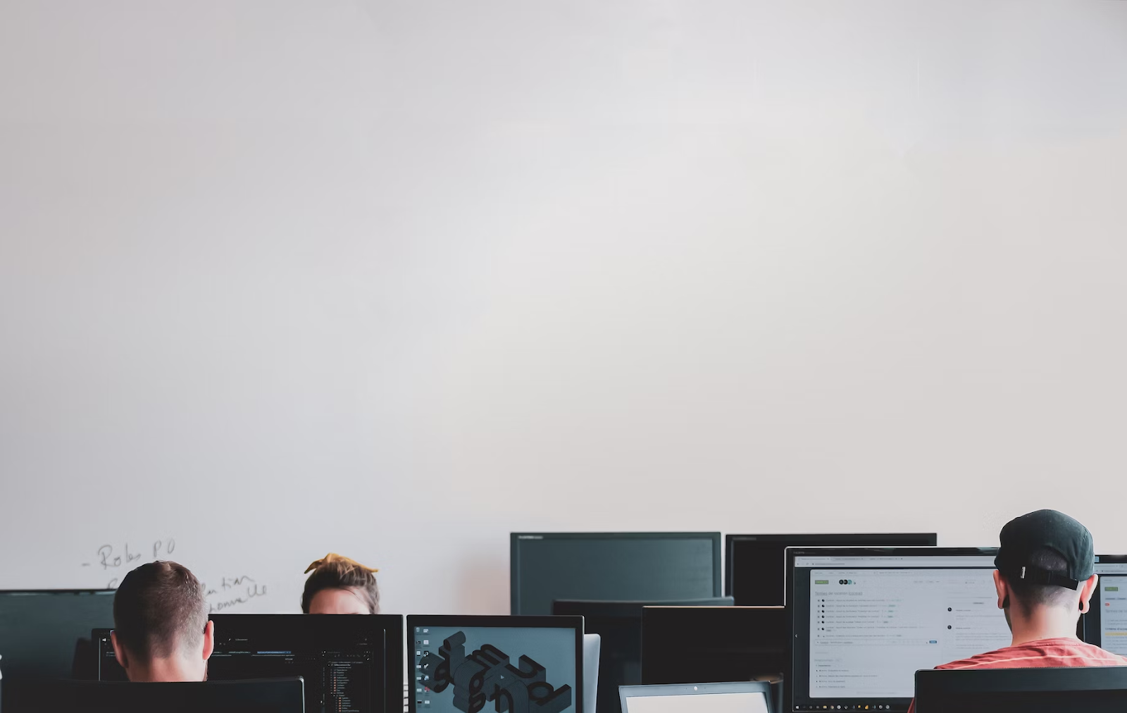 pessoas trabalhando em um escritório, na foto há diversos computadores com profissionais operando softwares.