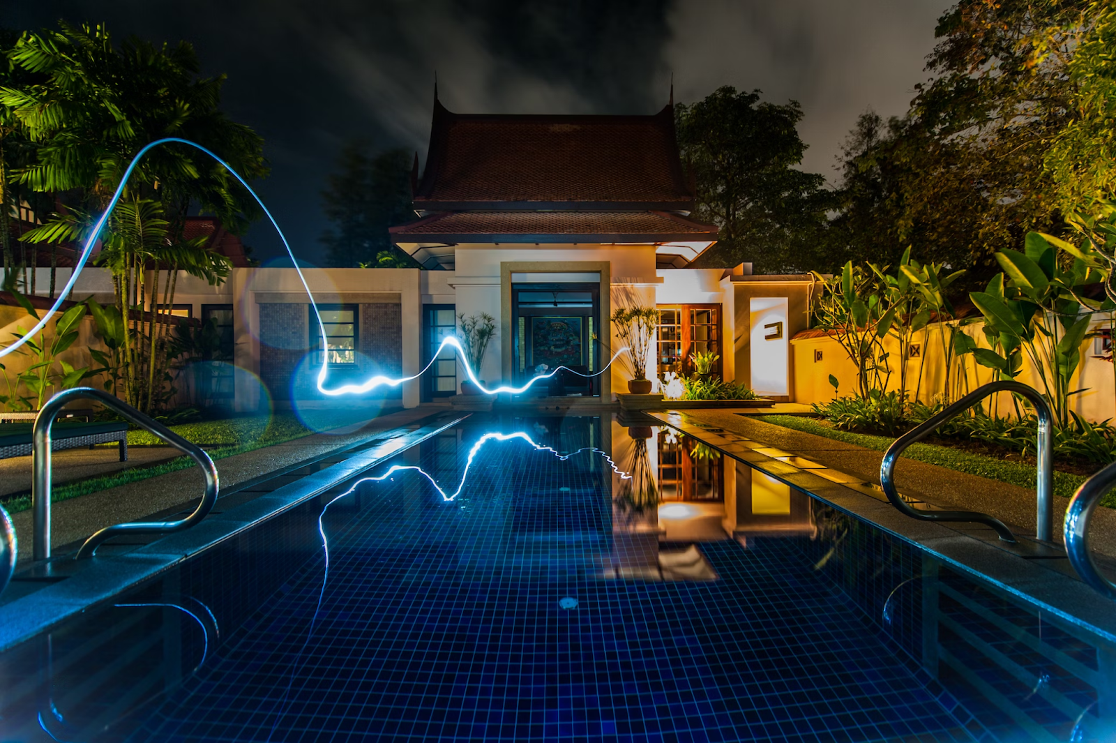 quintal de uma casa com uma piscina no centro e plantas nos lados. Há um raio de luz transitando do canto esquerdo até o centro da imagem.